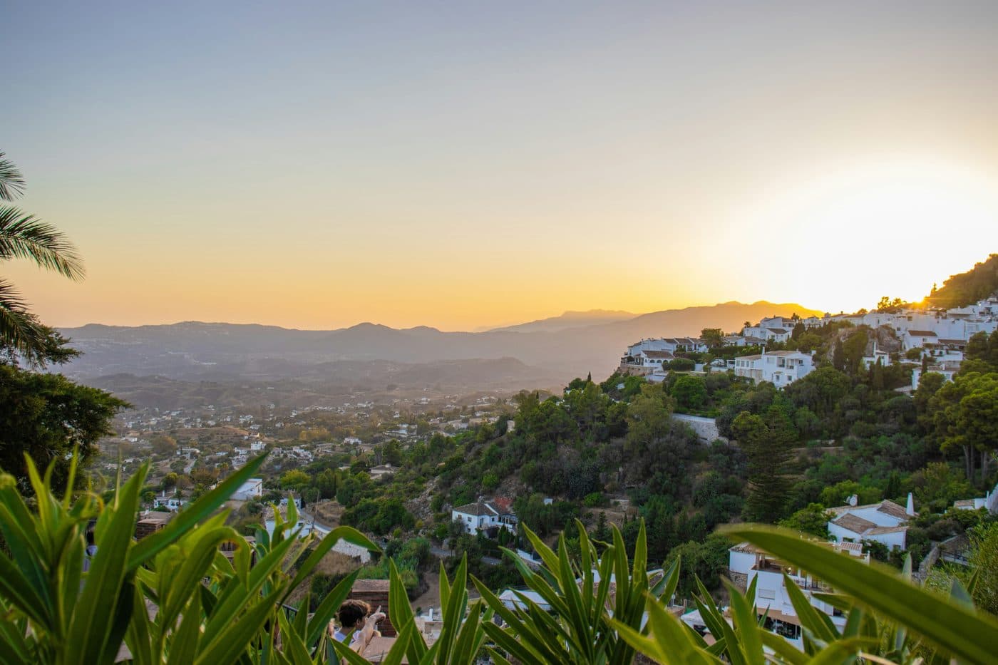White lane in Mijas Pueblo with whitewashed façades, flower pots and mountain views