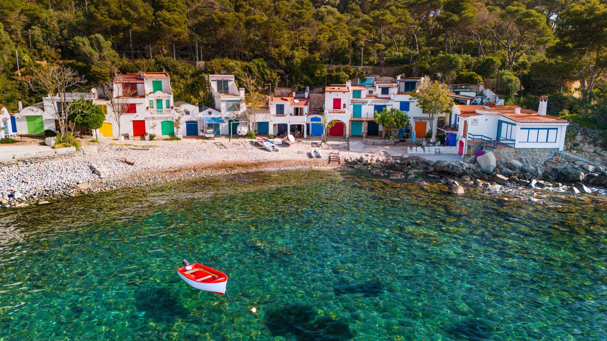 Coloured fishing cottages on a pebble bay on the Costa Brava